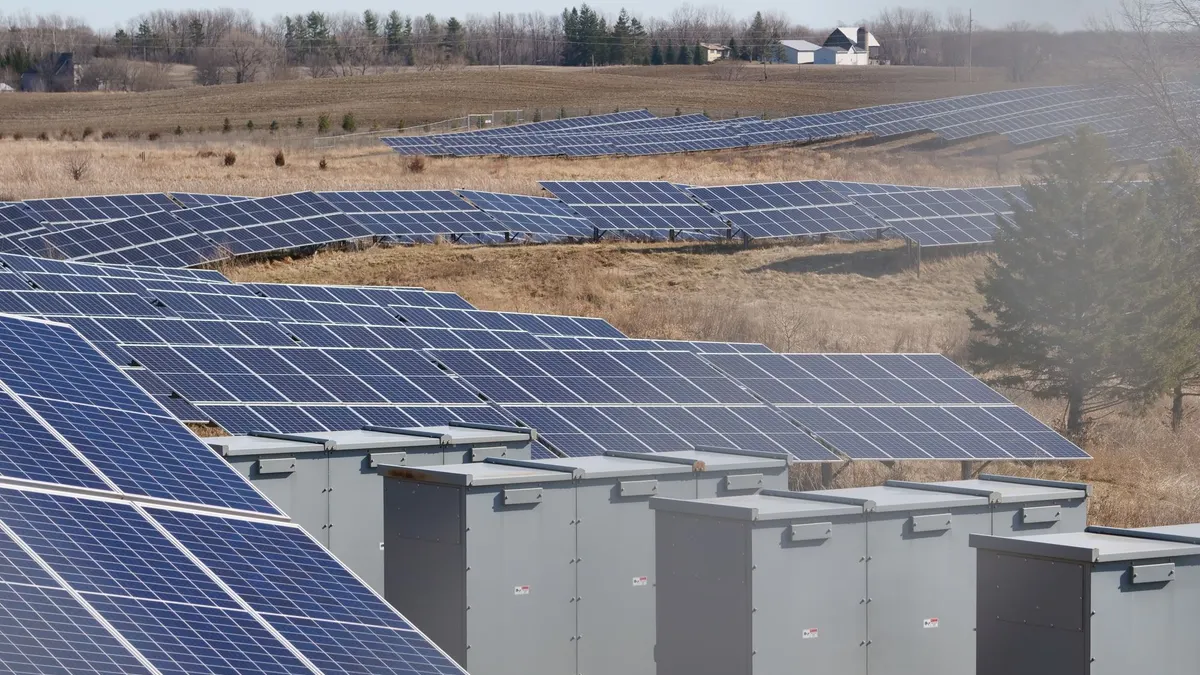 Outdoor battery and inverter cabinets beside a solar farm