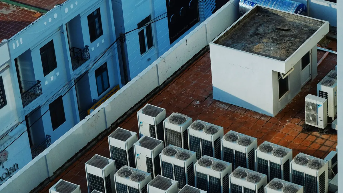 Rows of outdoor condenser units with fans on a roof